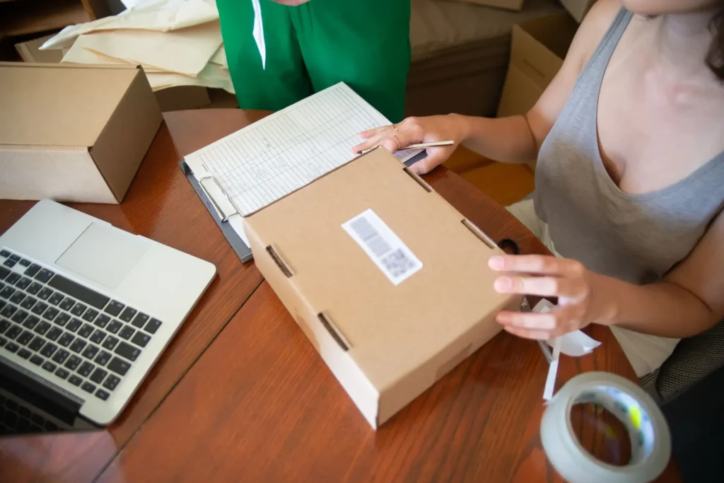 Online store team packing customer orders next to a laptop showing new orders