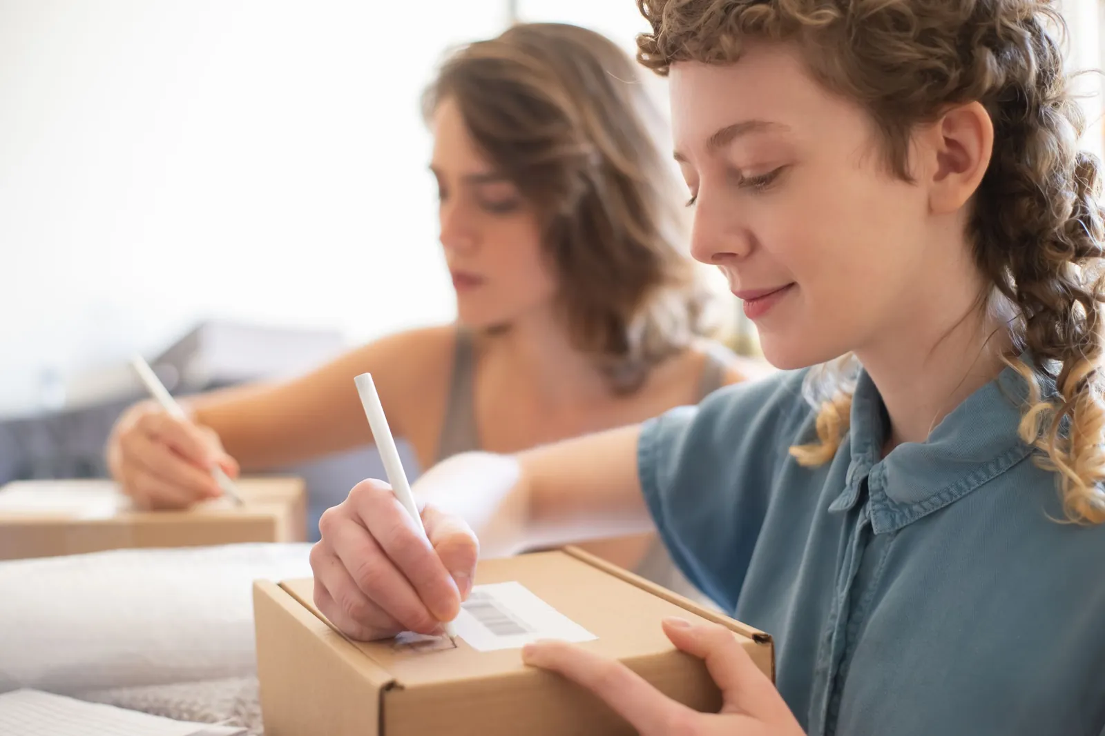 Seller writing delivery details on a parcel before courier pickup