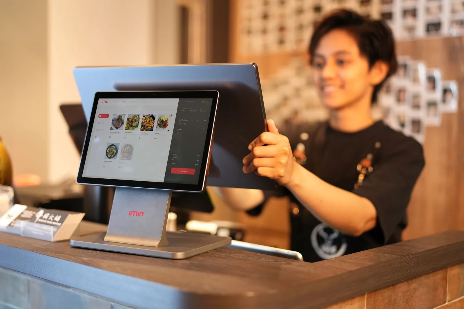 Cashier using a touchscreen POS connected to inventory and sales reports